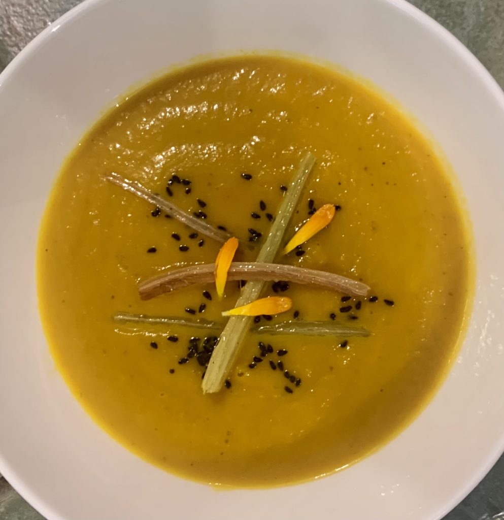 butternut soup in a white bowl with seeds on top